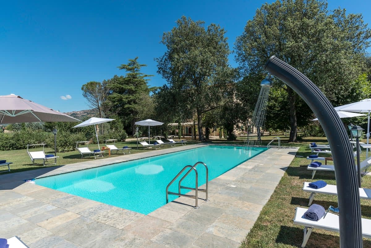 Villa della Cappella — the pool by day, with sun loungers and umbrellas