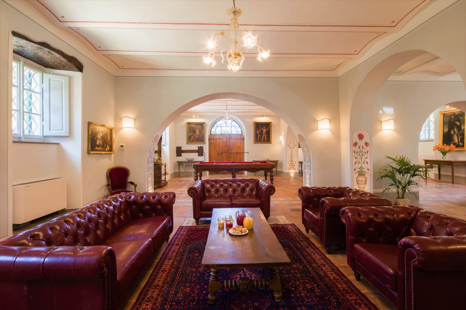 Villa della Cappella — the salon's leather Chesterfields, with the billiards table beyond