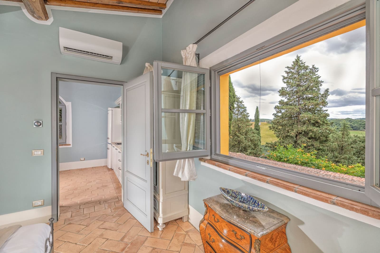 Villa Poggio d'Oro — a blue-walled room with a picture window over the park