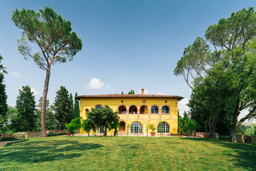 Villa Poggio d'Oro — the ochre façade across the lawn, framed by umbrella pines