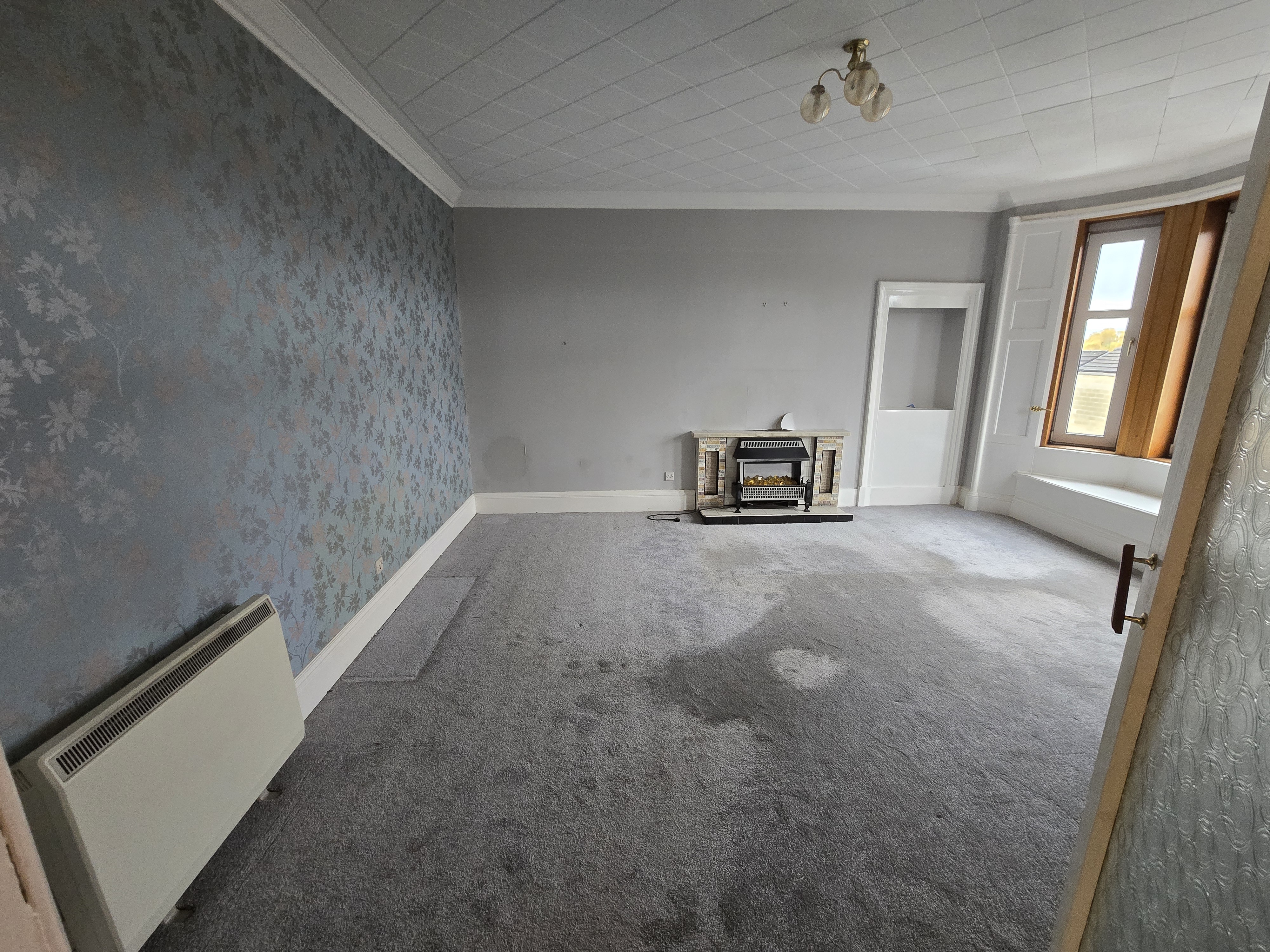 Living room before renovation — dated décor and worn carpet, full property refurbishment Wishaw, North Lanarkshire