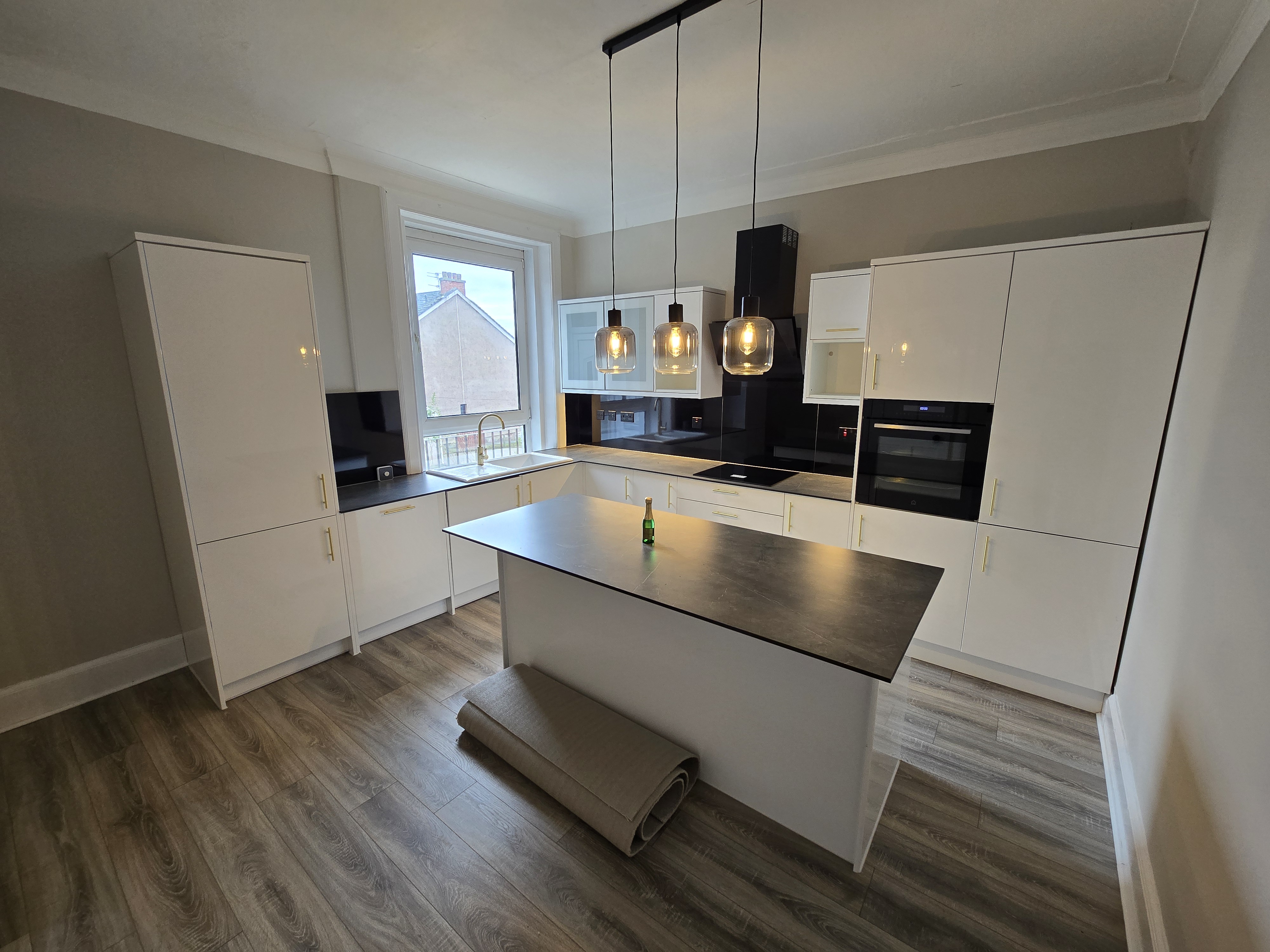 New kitchen after renovation — gloss white units, stone island and pendant lights, property refurbishment Wishaw Scotland