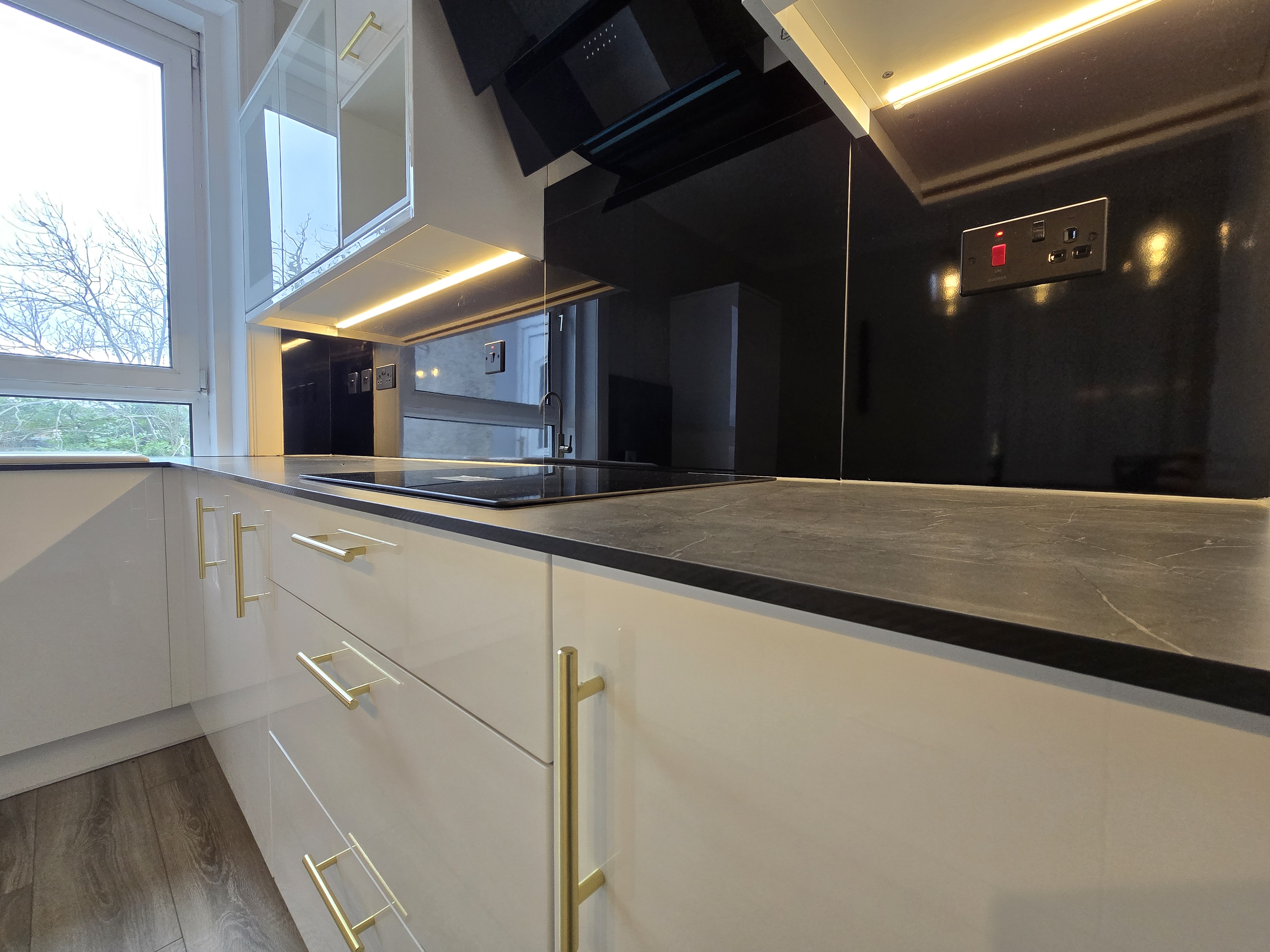 Kitchen side view showing gold hardware and under-cabinet lighting — property refurbishment North Lanarkshire Scotland