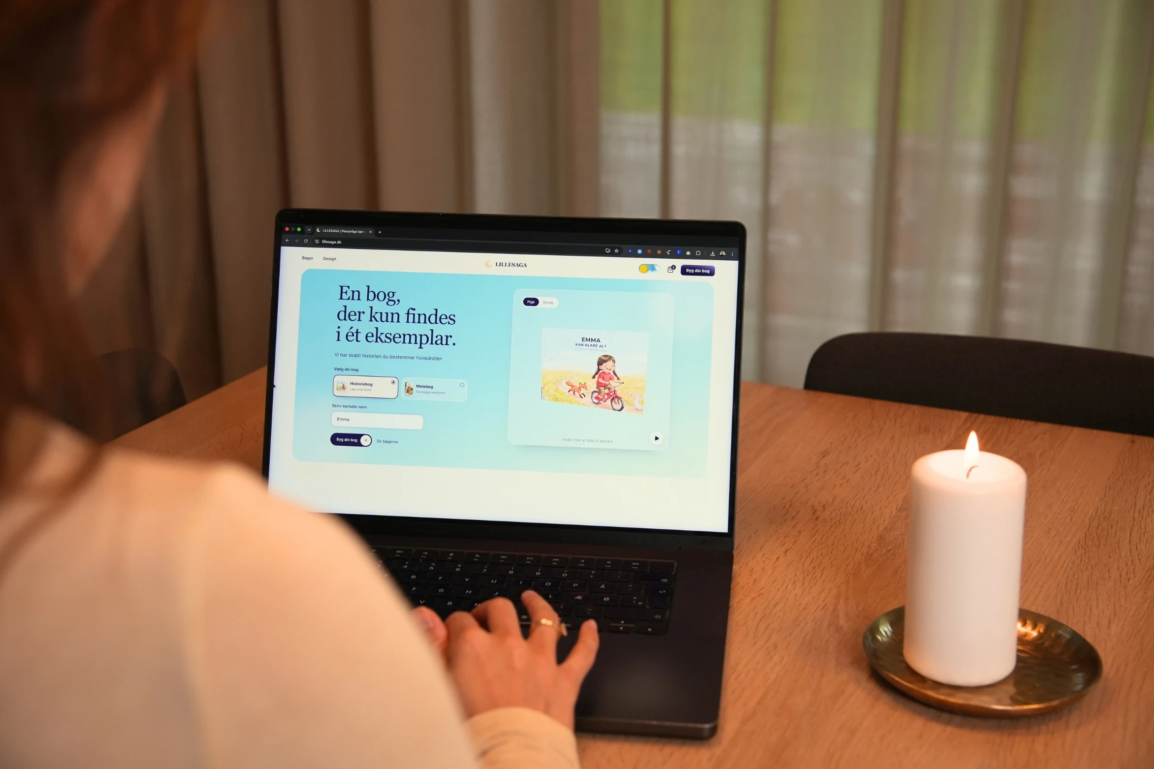 A parent designing a personalised book on a laptop at the dining table.