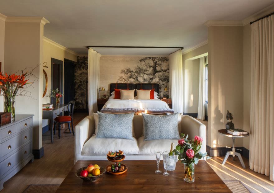 Garden View Suite bedroom with a king bed under a canopy, a sofa and fresh flowers