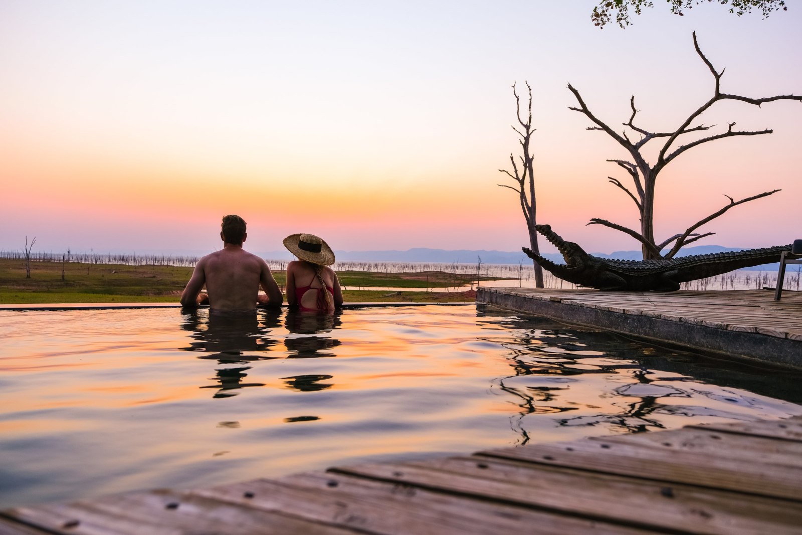 Guests in the infinity pool at sunset over Lake Kariba