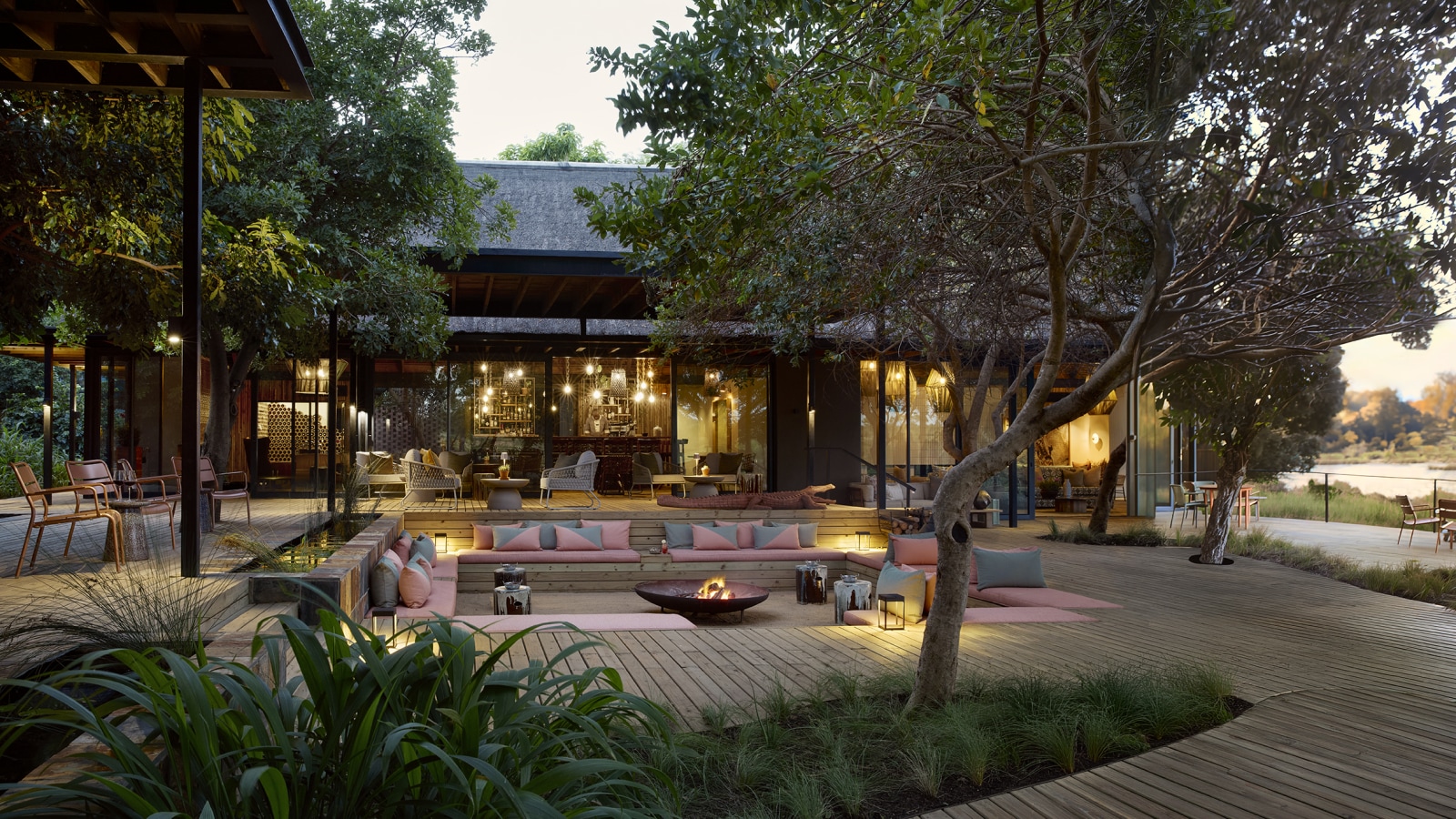 Main deck and fire pit under the trees at dusk, Lion Sands River Lodge