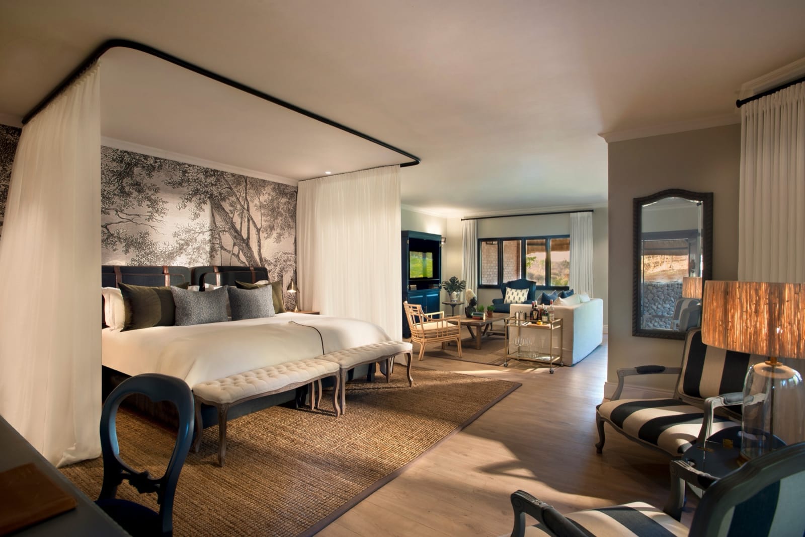Reserve View Suite with a canopied king bed, a striped armchair and a lounge area beyond