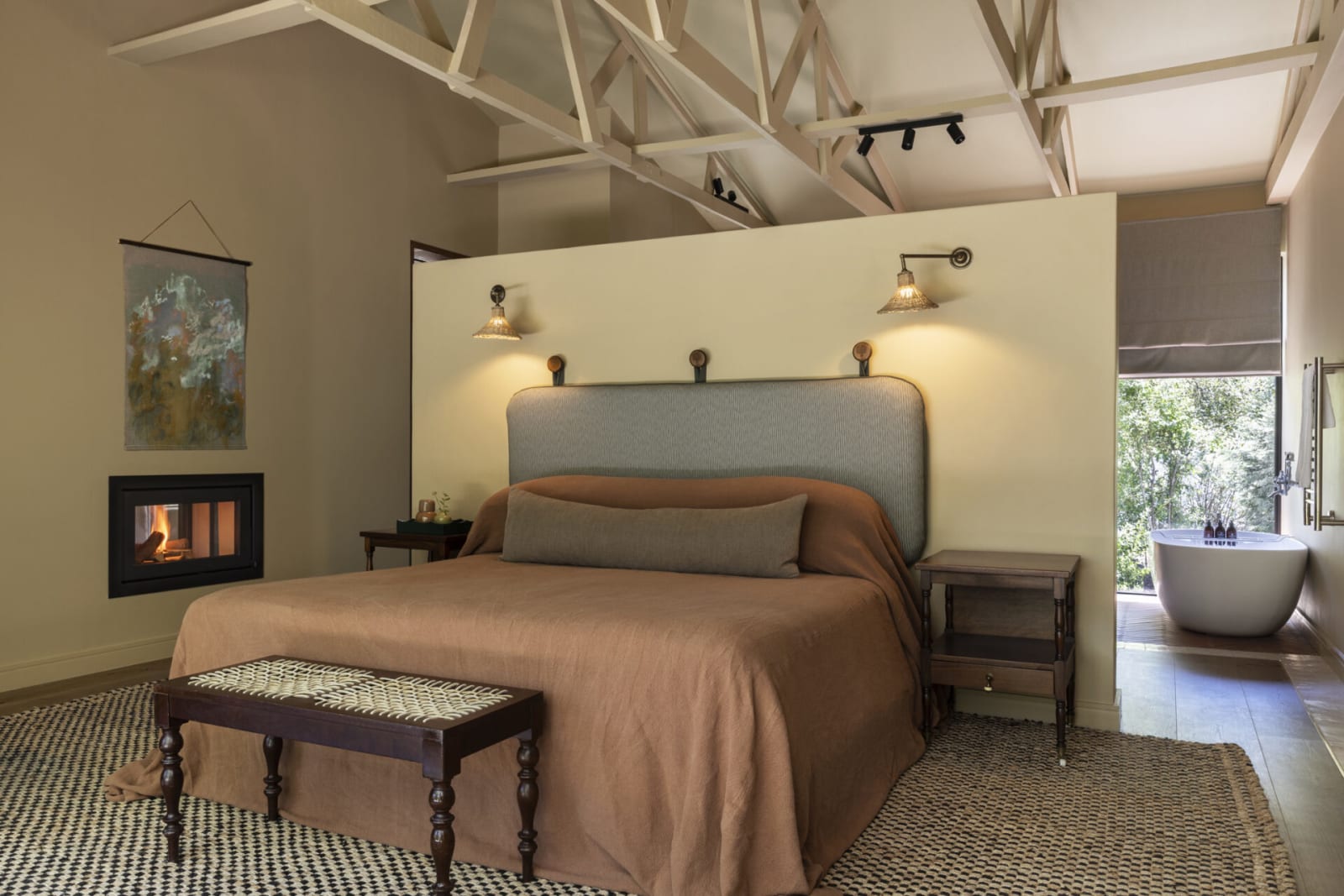 Bedroom in the couples' Clarence Cottage with a fireplace and freestanding bath beside the bed