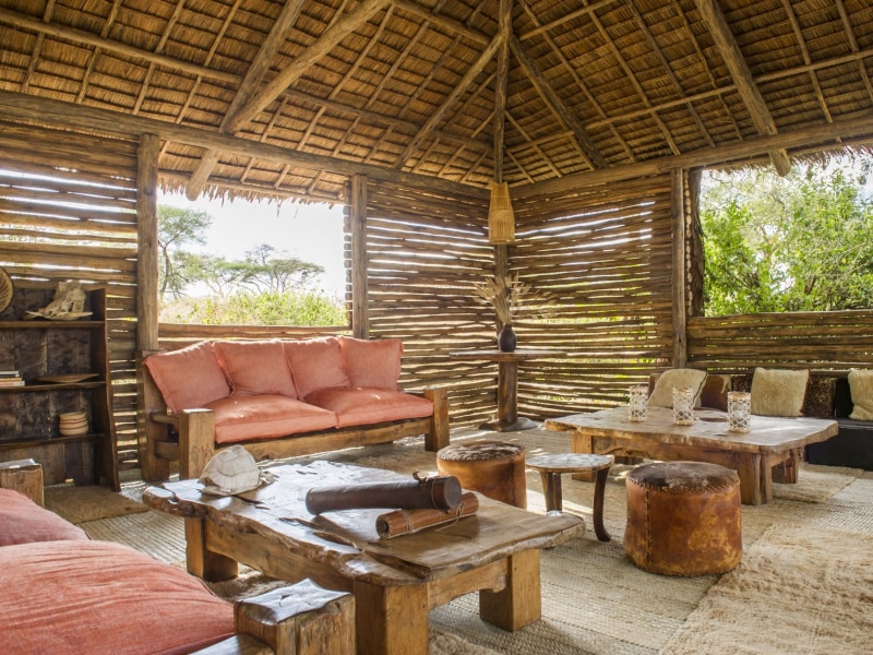 Cozy interior of a safari lodge with rustic wooden furniture and thatched roof
