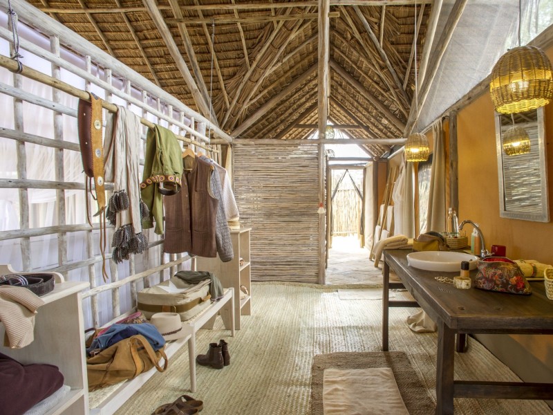Rustic interior of a luxury safari tent showing a dressing area and wooden vanity.