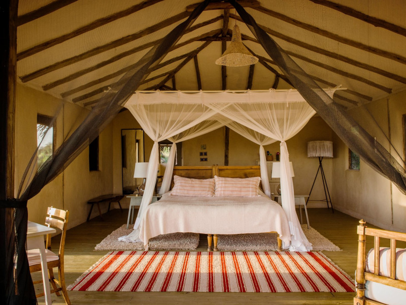 Interior of a luxury glamping tent with a canopy bed and mosquito net.