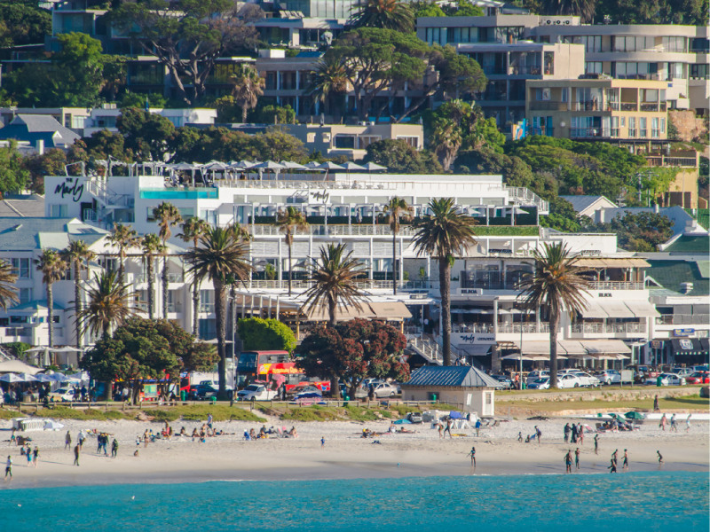 Exterior: white facade and rooftop pool above Camps Bay beach, Twelve Apostles behind