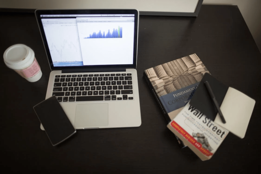 coffee, cellphone, fundamental and wall street book with note book and laptop on table