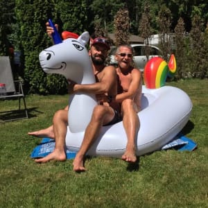 People riding inflatable unicorn on grass