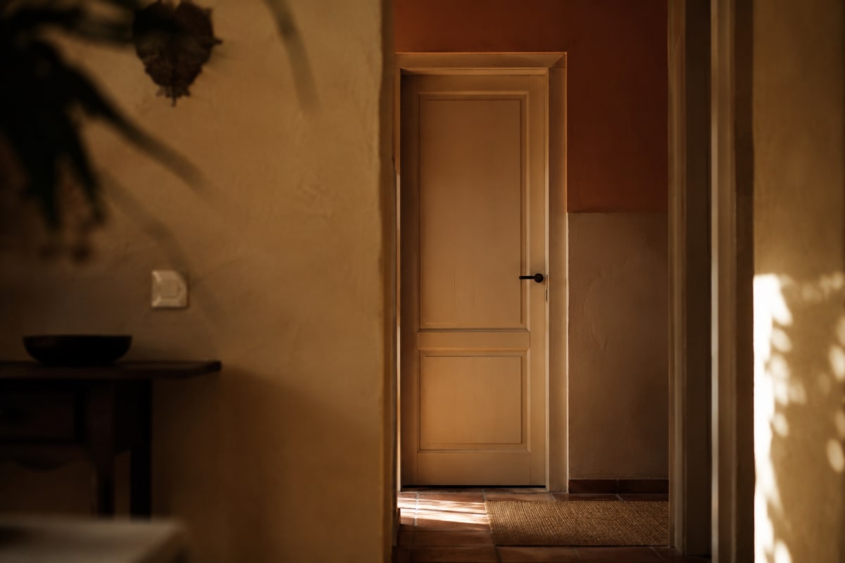 Puerta de habitación cerrada en casa mediterránea con luz cálida de pasillo