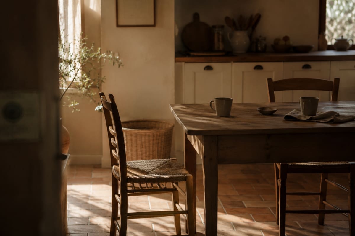 Dos sillas en cocina mediterránea con luz de tarde, una ligeramente apartada, sin personas