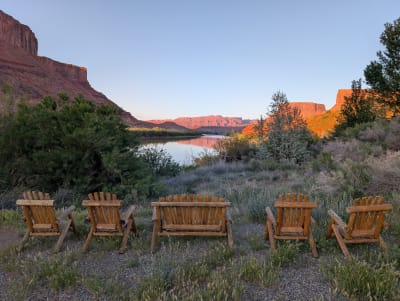 Wooden chairs by the Colorado river with sun setting on the red rocks