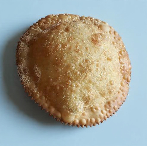 Golden fried seadas drizzled with dark amber honey on a ceramic plate
