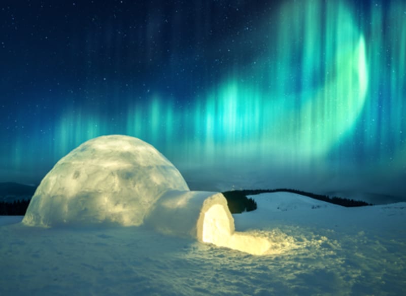 Glowing igloo under dramatic teal and blue aurora curtains