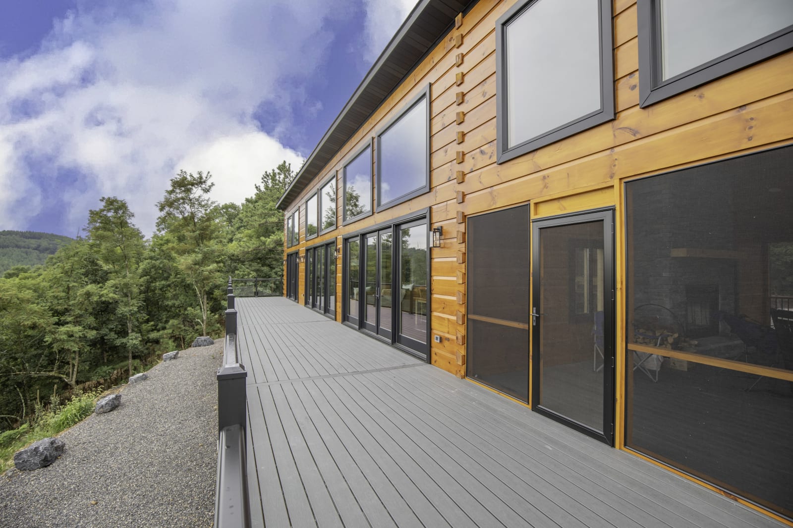 Covered deck with rocking chairs, timber railing, and panoramic mountain views