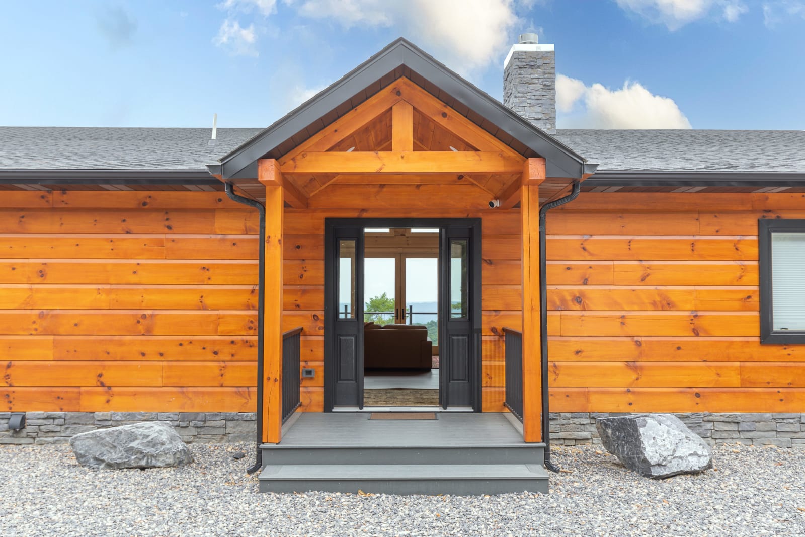 Front door entry of the Waite home with timber columns, cedar siding, and pendant lantern
