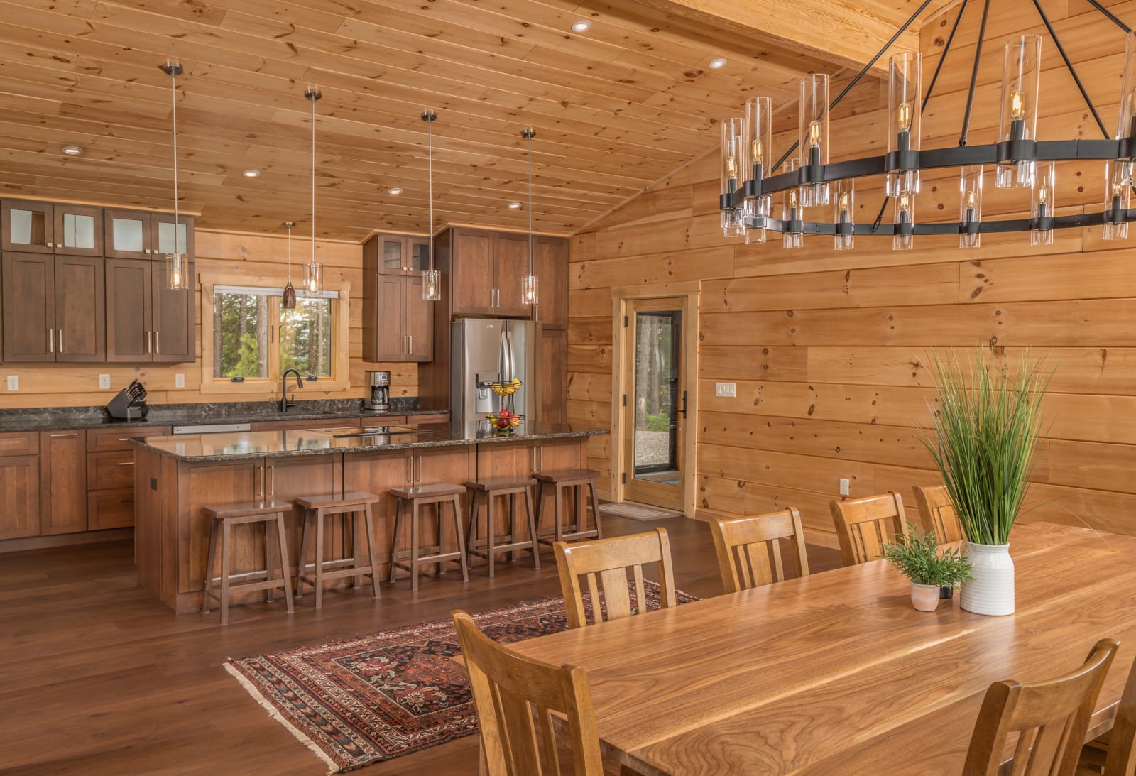 Kitchen with natural wood cabinets, stone countertops, bar seating, and pendant lights