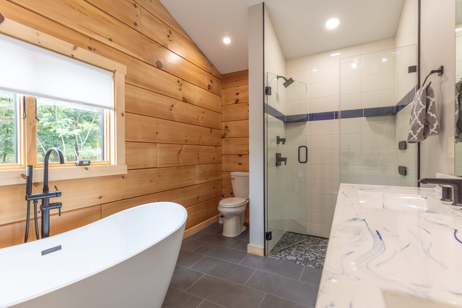 Master bathroom with freestanding soaking tub, walk-in tile shower, and blue accent tile