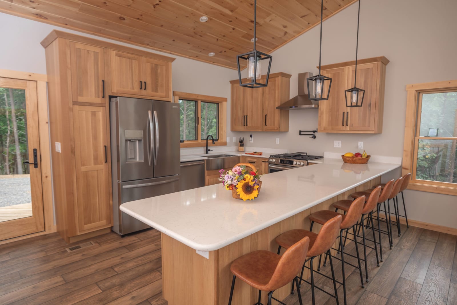 Kitchen island with natural wood cabinetry, pine tongue-and-groove ceiling, and modern pendant lights