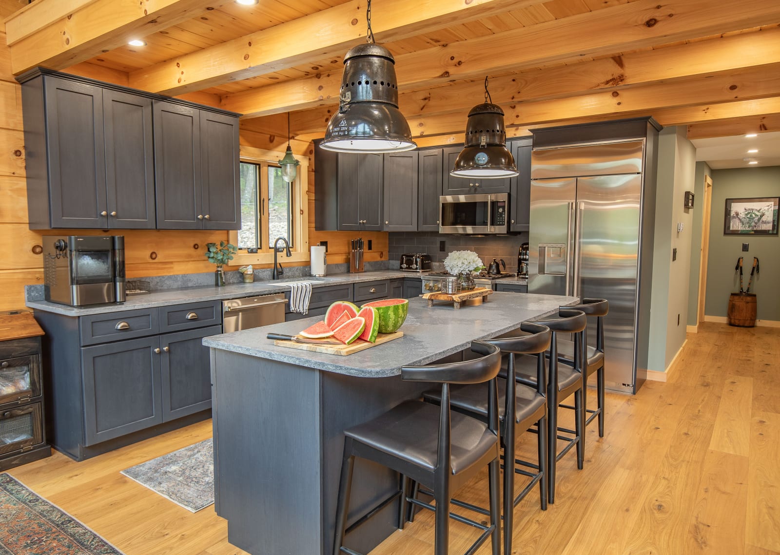 Modern gray kitchen cabinets contrasting natural log walls with pendant lighting
