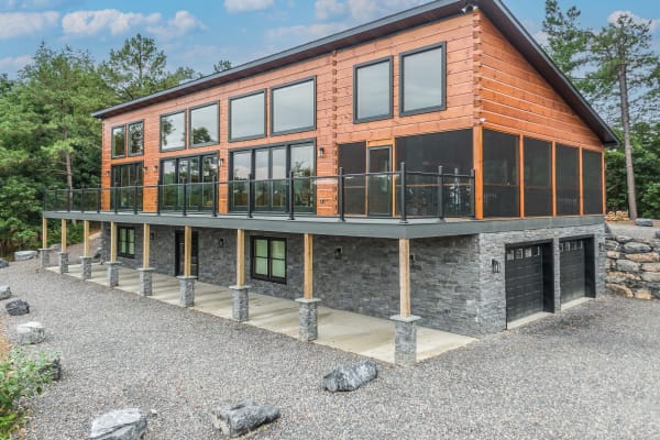 The Retreat — modern log home surrounded by trees with warm interior glow