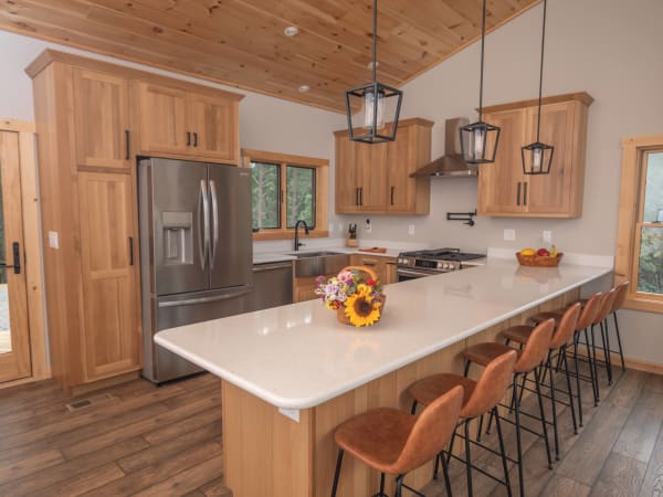 Kitchen with natural wood cabinets, quartz island, and bar seating in the Britton hybrid home