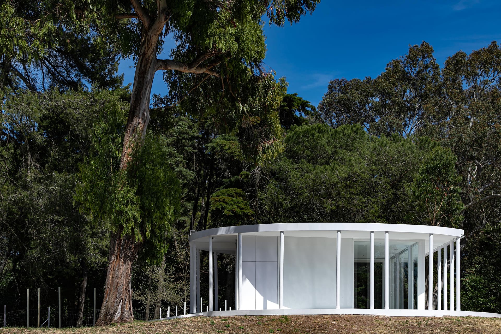 2-Vila-Lisboa-Lisboa - Aclamado por todos como o pulmão verde de Lisboa, Monsanto tem estado, de certa forma, abandonado à deterioração natural, carecendo de estruturas funcionais e apelativas de apoio aos habitantes da cidade de Lisboa. A par das novas tendências do estilo de vida dos portugueses, nomeadamente dos residentes nas grandes cidades, verifica-se uma procura crescente de espaços verdes, quer para a prática de desportos, quer para atividades de lazer ou apenas para usufruto e maior contacto com a natureza. Monsanto não é exceção, não obstante a falta de condições do parque florestal.
Monsanto tem uma nova “Floresta Branca”. Correspondendo às expectativas de muitos lisboetas, após um longo período de espera, vários projetos de requalificação estão a ser desenvolvidos pela Câmara Municipal de Lisboa e Juntas de Freguesia em diferentes zonas de Monsanto. A Junta de Freguesia de Benfica abriu um concurso público de reabilitação, o contrato entregue à Empresa CVZ Construções, que, em parceria com o gabinete de Arquitetura Bruno Câmara Arquitetos, desenvolveu todo o projeto de Concepção e Construção de um novo restaurante/bar com zonas exteriores, incluindo vários percursos pedonais e espaços lúdicos. Bruno Câmara Arquitectos adotou o conceito de “Uma Floresta Branca”, para criar um Projeto globalmente marcado pela cor branca, seguindo linhas minimalistas de Arquitetura Moderna e Contemporânea. Segundo o Arquiteto Bruno Câmara, Autor do Projeto,  o conceito “materializa todos os elementos propostos, integrando os mesmos no enquadramento paisagístico de Monsanto. 3.411 troncos de madeira pintados a branco formam vários espaços exteriores com diferentes funções, desde pequenos auditórios a espaços de lazer, envolvendo o espaço principal de restaurante/bar com a zona interior e exterior, que valoriza a espacialidade e ligação à natureza envolvente.”
A nova construção destaca-se assim pelo seu branco minimalista inserido no verde de Monsanto, que cria harmonia com os espaços envolventes, quer pelas suas linhas curvas, quer pelos materiais utilizados, conferindo-lhes modernidade.