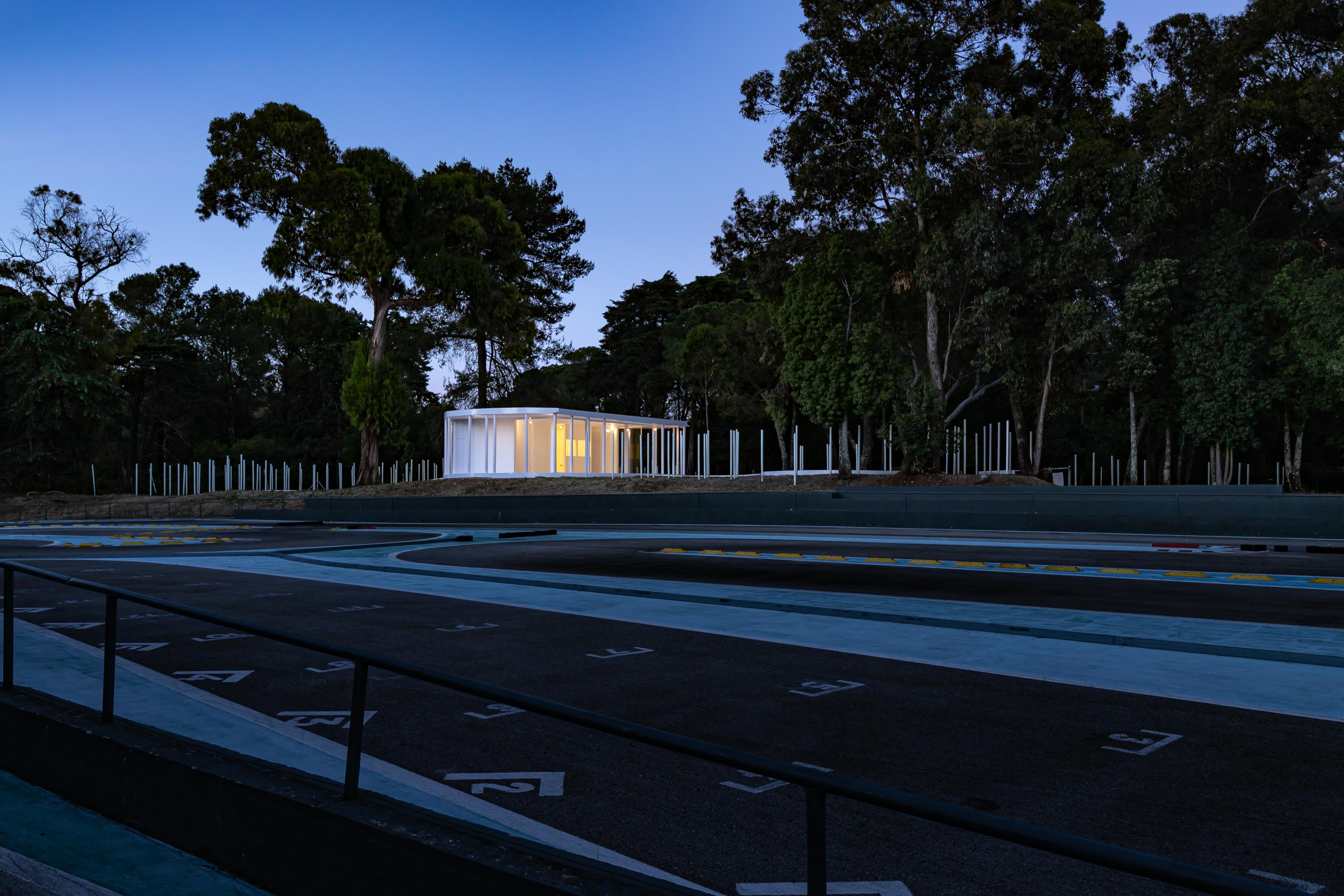 4-Vila-Lisboa-Lisboa - Aclamado por todos como o pulmão verde de Lisboa, Monsanto tem estado, de certa forma, abandonado à deterioração natural, carecendo de estruturas funcionais e apelativas de apoio aos habitantes da cidade de Lisboa. A par das novas tendências do estilo de vida dos portugueses, nomeadamente dos residentes nas grandes cidades, verifica-se uma procura crescente de espaços verdes, quer para a prática de desportos, quer para atividades de lazer ou apenas para usufruto e maior contacto com a natureza. Monsanto não é exceção, não obstante a falta de condições do parque florestal.
Monsanto tem uma nova “Floresta Branca”. Correspondendo às expectativas de muitos lisboetas, após um longo período de espera, vários projetos de requalificação estão a ser desenvolvidos pela Câmara Municipal de Lisboa e Juntas de Freguesia em diferentes zonas de Monsanto. A Junta de Freguesia de Benfica abriu um concurso público de reabilitação, o contrato entregue à Empresa CVZ Construções, que, em parceria com o gabinete de Arquitetura Bruno Câmara Arquitetos, desenvolveu todo o projeto de Concepção e Construção de um novo restaurante/bar com zonas exteriores, incluindo vários percursos pedonais e espaços lúdicos. Bruno Câmara Arquitectos adotou o conceito de “Uma Floresta Branca”, para criar um Projeto globalmente marcado pela cor branca, seguindo linhas minimalistas de Arquitetura Moderna e Contemporânea. Segundo o Arquiteto Bruno Câmara, Autor do Projeto,  o conceito “materializa todos os elementos propostos, integrando os mesmos no enquadramento paisagístico de Monsanto. 3.411 troncos de madeira pintados a branco formam vários espaços exteriores com diferentes funções, desde pequenos auditórios a espaços de lazer, envolvendo o espaço principal de restaurante/bar com a zona interior e exterior, que valoriza a espacialidade e ligação à natureza envolvente.”
A nova construção destaca-se assim pelo seu branco minimalista inserido no verde de Monsanto, que cria harmonia com os espaços envolventes, quer pelas suas linhas curvas, quer pelos materiais utilizados, conferindo-lhes modernidade.