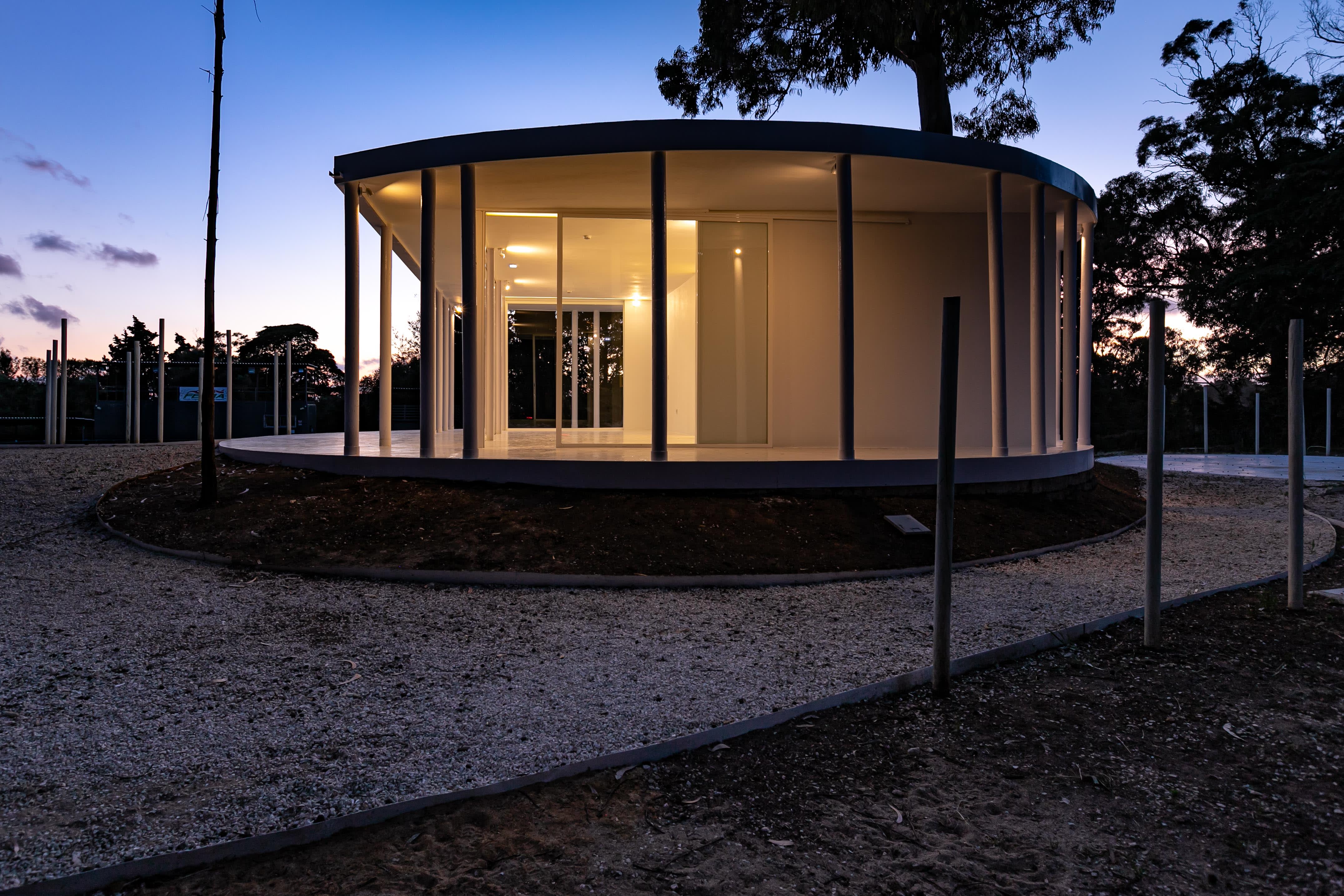 7-Vila-Lisboa-Lisboa - Aclamado por todos como o pulmão verde de Lisboa, Monsanto tem estado, de certa forma, abandonado à deterioração natural, carecendo de estruturas funcionais e apelativas de apoio aos habitantes da cidade de Lisboa. A par das novas tendências do estilo de vida dos portugueses, nomeadamente dos residentes nas grandes cidades, verifica-se uma procura crescente de espaços verdes, quer para a prática de desportos, quer para atividades de lazer ou apenas para usufruto e maior contacto com a natureza. Monsanto não é exceção, não obstante a falta de condições do parque florestal.
Monsanto tem uma nova “Floresta Branca”. Correspondendo às expectativas de muitos lisboetas, após um longo período de espera, vários projetos de requalificação estão a ser desenvolvidos pela Câmara Municipal de Lisboa e Juntas de Freguesia em diferentes zonas de Monsanto. A Junta de Freguesia de Benfica abriu um concurso público de reabilitação, o contrato entregue à Empresa CVZ Construções, que, em parceria com o gabinete de Arquitetura Bruno Câmara Arquitetos, desenvolveu todo o projeto de Concepção e Construção de um novo restaurante/bar com zonas exteriores, incluindo vários percursos pedonais e espaços lúdicos. Bruno Câmara Arquitectos adotou o conceito de “Uma Floresta Branca”, para criar um Projeto globalmente marcado pela cor branca, seguindo linhas minimalistas de Arquitetura Moderna e Contemporânea. Segundo o Arquiteto Bruno Câmara, Autor do Projeto,  o conceito “materializa todos os elementos propostos, integrando os mesmos no enquadramento paisagístico de Monsanto. 3.411 troncos de madeira pintados a branco formam vários espaços exteriores com diferentes funções, desde pequenos auditórios a espaços de lazer, envolvendo o espaço principal de restaurante/bar com a zona interior e exterior, que valoriza a espacialidade e ligação à natureza envolvente.”
A nova construção destaca-se assim pelo seu branco minimalista inserido no verde de Monsanto, que cria harmonia com os espaços envolventes, quer pelas suas linhas curvas, quer pelos materiais utilizados, conferindo-lhes modernidade.