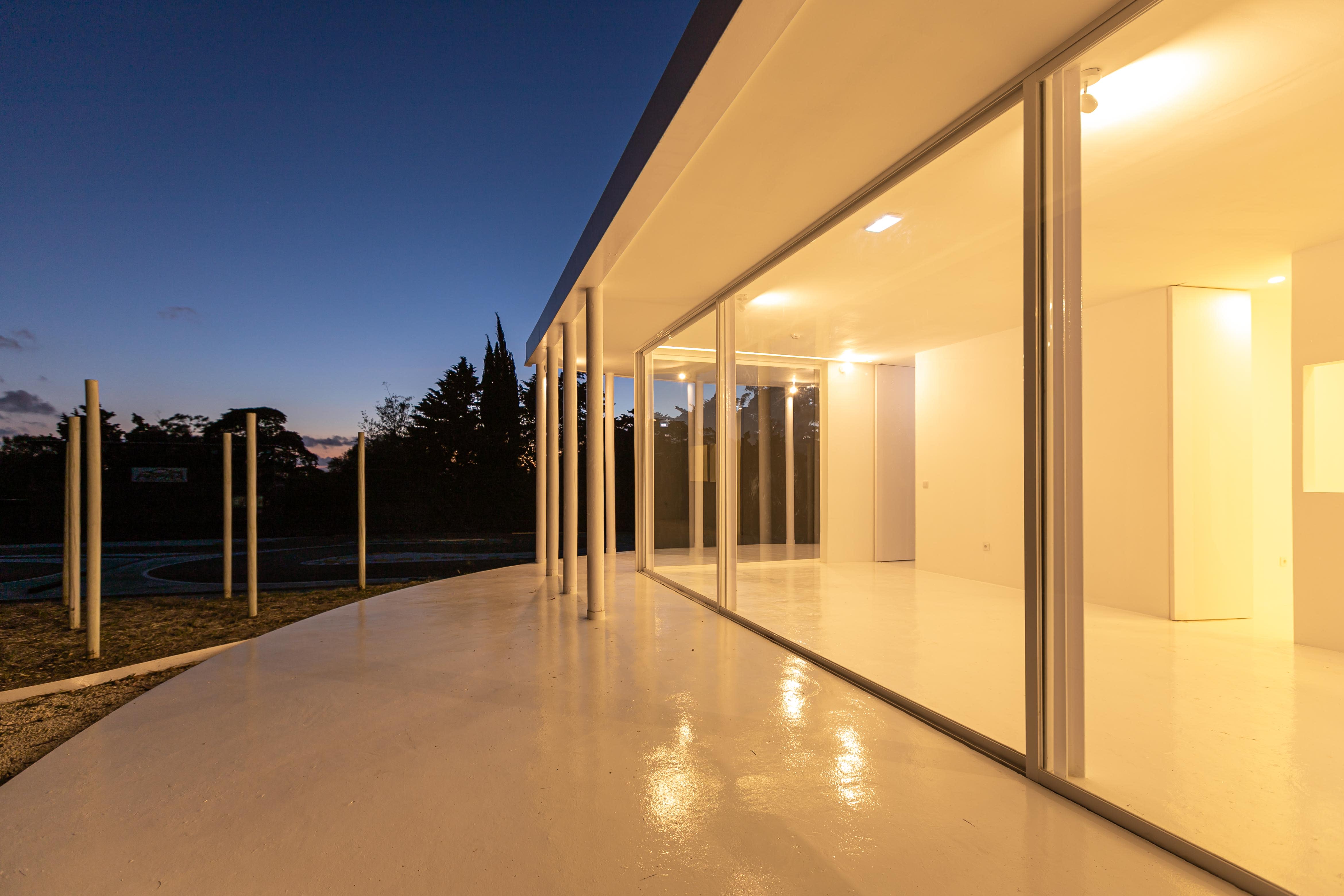 9-Vila-Lisboa-Lisboa - Aclamado por todos como o pulmão verde de Lisboa, Monsanto tem estado, de certa forma, abandonado à deterioração natural, carecendo de estruturas funcionais e apelativas de apoio aos habitantes da cidade de Lisboa. A par das novas tendências do estilo de vida dos portugueses, nomeadamente dos residentes nas grandes cidades, verifica-se uma procura crescente de espaços verdes, quer para a prática de desportos, quer para atividades de lazer ou apenas para usufruto e maior contacto com a natureza. Monsanto não é exceção, não obstante a falta de condições do parque florestal.
Monsanto tem uma nova “Floresta Branca”. Correspondendo às expectativas de muitos lisboetas, após um longo período de espera, vários projetos de requalificação estão a ser desenvolvidos pela Câmara Municipal de Lisboa e Juntas de Freguesia em diferentes zonas de Monsanto. A Junta de Freguesia de Benfica abriu um concurso público de reabilitação, o contrato entregue à Empresa CVZ Construções, que, em parceria com o gabinete de Arquitetura Bruno Câmara Arquitetos, desenvolveu todo o projeto de Concepção e Construção de um novo restaurante/bar com zonas exteriores, incluindo vários percursos pedonais e espaços lúdicos. Bruno Câmara Arquitectos adotou o conceito de “Uma Floresta Branca”, para criar um Projeto globalmente marcado pela cor branca, seguindo linhas minimalistas de Arquitetura Moderna e Contemporânea. Segundo o Arquiteto Bruno Câmara, Autor do Projeto,  o conceito “materializa todos os elementos propostos, integrando os mesmos no enquadramento paisagístico de Monsanto. 3.411 troncos de madeira pintados a branco formam vários espaços exteriores com diferentes funções, desde pequenos auditórios a espaços de lazer, envolvendo o espaço principal de restaurante/bar com a zona interior e exterior, que valoriza a espacialidade e ligação à natureza envolvente.”
A nova construção destaca-se assim pelo seu branco minimalista inserido no verde de Monsanto, que cria harmonia com os espaços envolventes, quer pelas suas linhas curvas, quer pelos materiais utilizados, conferindo-lhes modernidade.