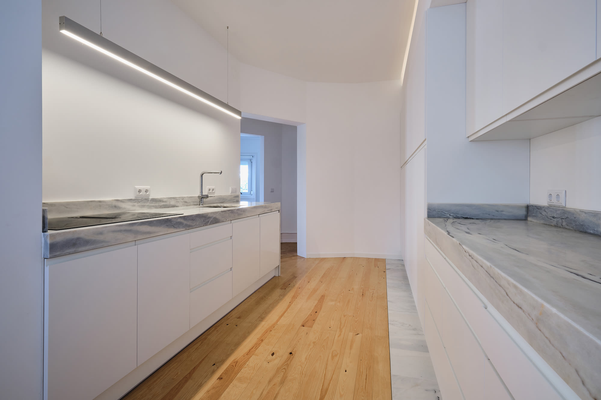 9-Apartamento-Lisboa-Lisboa - O apartamento insere-se num edifício de gaveto entre a Avenida de Berna e Avenida Marquês de Tomar no bairro das Avenidas Novas, localizado na zona central de Lisboa, junto à Avenida da República, uma das principais vias da cidade. A Avenida de Berna tem uma longa história de Glamour e estilo de vida de classe alta e essa cultura esteve presente na nossa forma de abordar o Projeto.
O bairro é definido por vias largas de dois sentidos, logradouros ajardinados e coerência estética no desenho das fachadas, tornando Avenida de Berna numa das zonas mais valorizadas de Lisboa. O edifício  é composto por um piso térreo e quatro pisos seguintes. A construção é definida por fundações em alvenaria de pedra, que é o mesmo material presente nas paredes exteriores. Os interiores por si, encontram-se em tijolo maciço, com uma laje mista e cobertura em telha marselha assente em barrotes de madeira. São criadas novas aberturas interiores, o layout da cozinha é alterado para permitir a continuidade e fluidez espacial entre o espaço social definido pelas divisões conectadas.
O alçado principal é definido por uma métrica de vãos com de guardas metálicas, assim como vãos exteriores em alumínio com vidro duplo e com uma cobertura de duas águas em cerâmica. Com a intervenção da CVZ Construções, nasce uma nova zona social. Uma nova disposição, com maior espacialidade e luminosidade, na cozinha, sala e Instalações Sanitárias. O novo espaço traz mobiliário fixo de biblioteca e zonas de iluminação indireta.