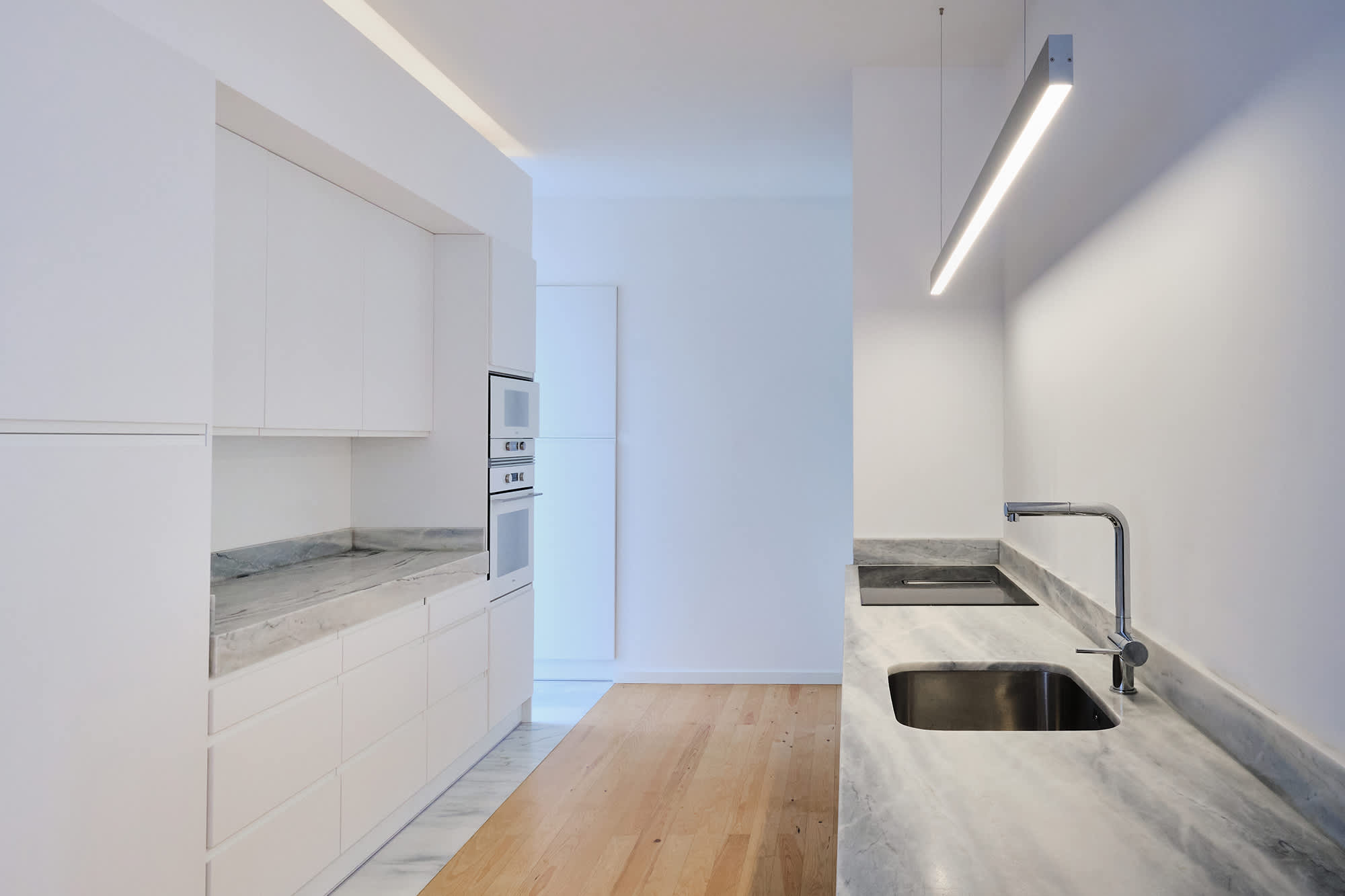 11-Apartamento-Lisboa-Lisboa - O apartamento insere-se num edifício de gaveto entre a Avenida de Berna e Avenida Marquês de Tomar no bairro das Avenidas Novas, localizado na zona central de Lisboa, junto à Avenida da República, uma das principais vias da cidade. A Avenida de Berna tem uma longa história de Glamour e estilo de vida de classe alta e essa cultura esteve presente na nossa forma de abordar o Projeto.
O bairro é definido por vias largas de dois sentidos, logradouros ajardinados e coerência estética no desenho das fachadas, tornando Avenida de Berna numa das zonas mais valorizadas de Lisboa. O edifício  é composto por um piso térreo e quatro pisos seguintes. A construção é definida por fundações em alvenaria de pedra, que é o mesmo material presente nas paredes exteriores. Os interiores por si, encontram-se em tijolo maciço, com uma laje mista e cobertura em telha marselha assente em barrotes de madeira. São criadas novas aberturas interiores, o layout da cozinha é alterado para permitir a continuidade e fluidez espacial entre o espaço social definido pelas divisões conectadas.
O alçado principal é definido por uma métrica de vãos com de guardas metálicas, assim como vãos exteriores em alumínio com vidro duplo e com uma cobertura de duas águas em cerâmica. Com a intervenção da CVZ Construções, nasce uma nova zona social. Uma nova disposição, com maior espacialidade e luminosidade, na cozinha, sala e Instalações Sanitárias. O novo espaço traz mobiliário fixo de biblioteca e zonas de iluminação indireta.