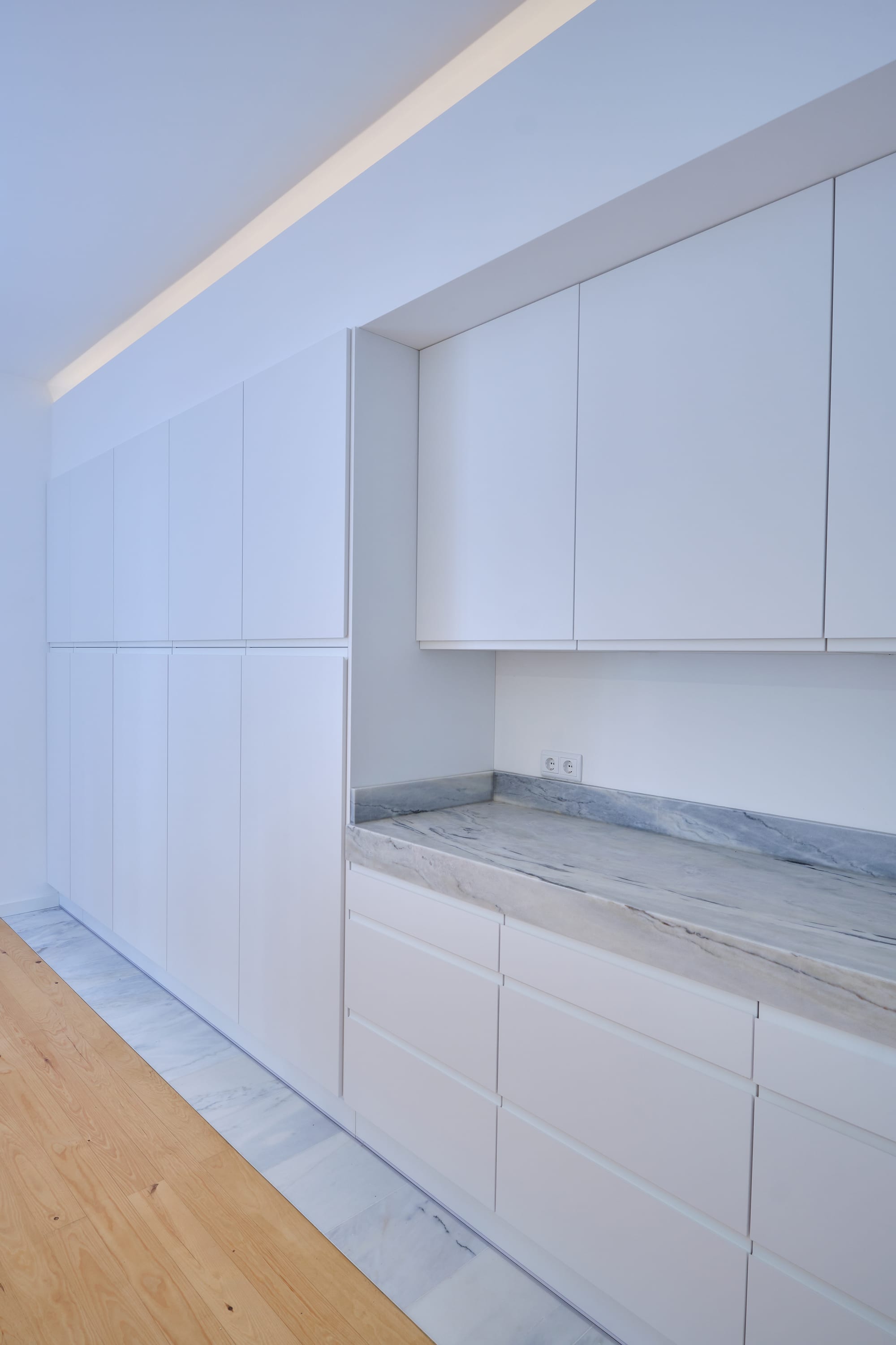 12-Apartamento-Lisboa-Lisboa - O apartamento insere-se num edifício de gaveto entre a Avenida de Berna e Avenida Marquês de Tomar no bairro das Avenidas Novas, localizado na zona central de Lisboa, junto à Avenida da República, uma das principais vias da cidade. A Avenida de Berna tem uma longa história de Glamour e estilo de vida de classe alta e essa cultura esteve presente na nossa forma de abordar o Projeto.
O bairro é definido por vias largas de dois sentidos, logradouros ajardinados e coerência estética no desenho das fachadas, tornando Avenida de Berna numa das zonas mais valorizadas de Lisboa. O edifício  é composto por um piso térreo e quatro pisos seguintes. A construção é definida por fundações em alvenaria de pedra, que é o mesmo material presente nas paredes exteriores. Os interiores por si, encontram-se em tijolo maciço, com uma laje mista e cobertura em telha marselha assente em barrotes de madeira. São criadas novas aberturas interiores, o layout da cozinha é alterado para permitir a continuidade e fluidez espacial entre o espaço social definido pelas divisões conectadas.
O alçado principal é definido por uma métrica de vãos com de guardas metálicas, assim como vãos exteriores em alumínio com vidro duplo e com uma cobertura de duas águas em cerâmica. Com a intervenção da CVZ Construções, nasce uma nova zona social. Uma nova disposição, com maior espacialidade e luminosidade, na cozinha, sala e Instalações Sanitárias. O novo espaço traz mobiliário fixo de biblioteca e zonas de iluminação indireta.