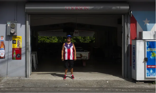 Adjuntas (PUERTO RICO), 06/24/2026. A man smokes in the doorway of a bar in Adjuntas. | Thais Llorca for The Parlor Magazine
