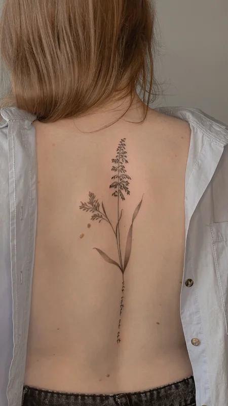 Back tattoo of field grass and an inscription