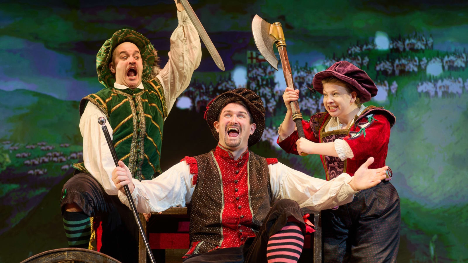 Three performers in colourful Tudor costumes, with a sword and axe raised over a seated figure wearing striped stockings.