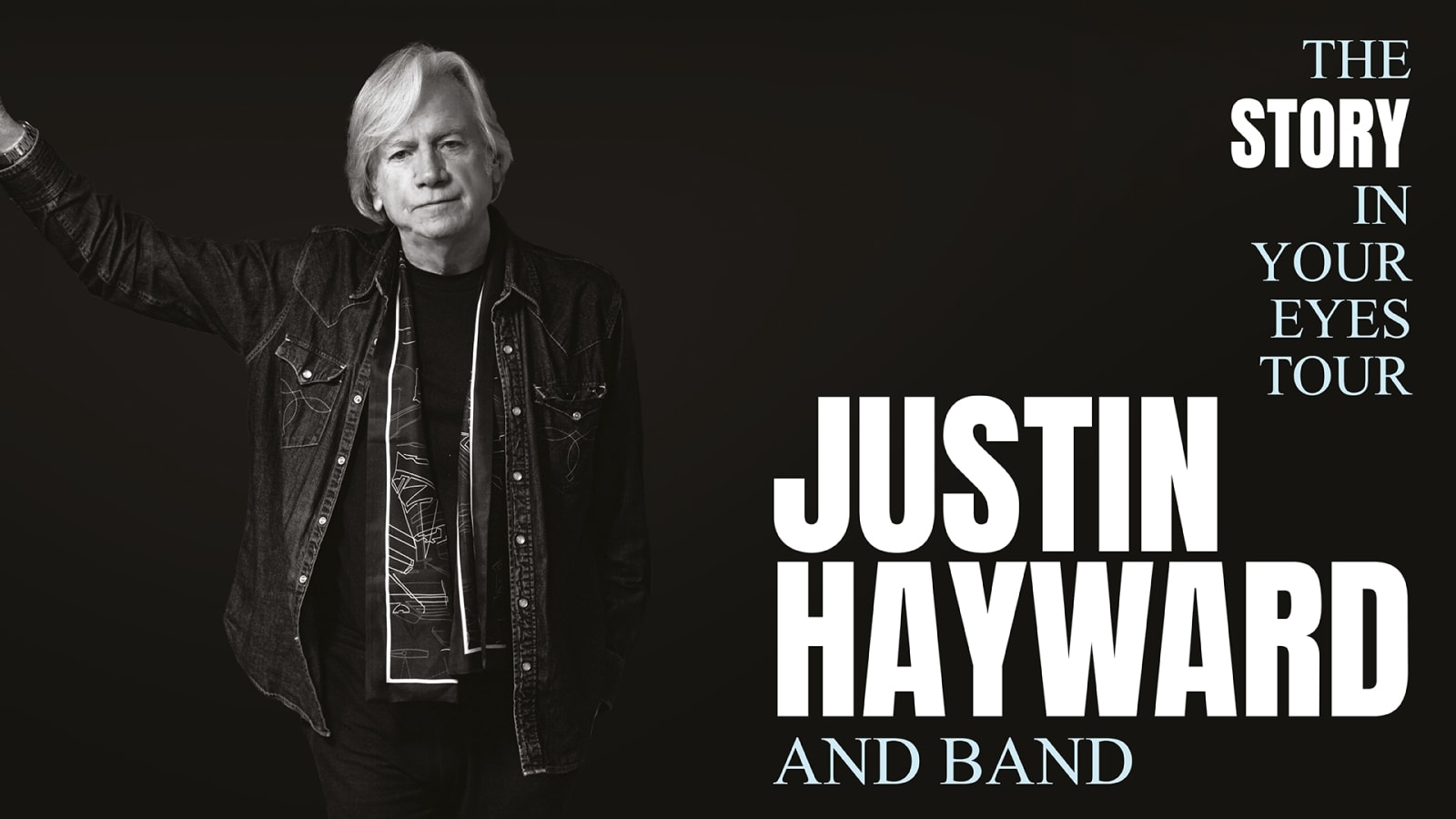 Black and white promotional image with bold white text reading 'The Story In Your Eyes Tour, Justin Hayward And Band', showing a silver-haired figure in a dark denim shirt with one arm raised