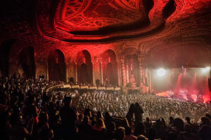 Kings theatre house with audience members. The shot is from the mezzanine and features a wide shot of a full house as a performer is on stage.