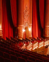 A view of empty mezzanine and box seats in Kings Theatre house. The ornate gold detailing found on the mezzanine overhang can be seen.