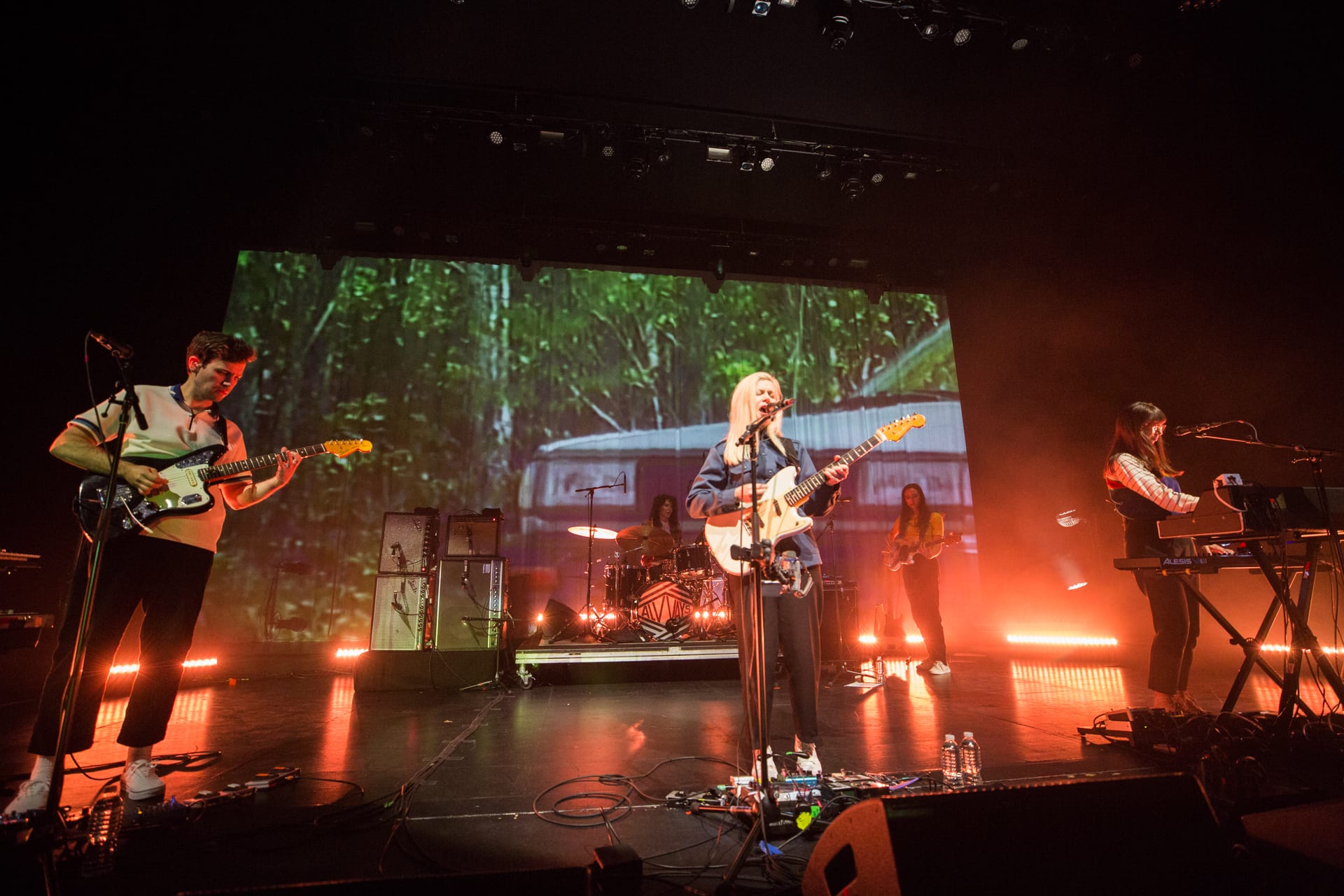 three musicians on stage playing guitar and piano