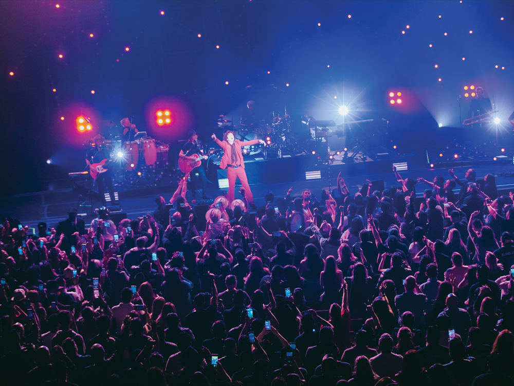 A shot of Bunbury performing on stage with a large crowd cheering along. 