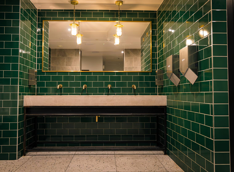 Brass taps and green tile in the washrooms at XF Manchester