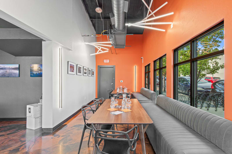 Tasting room with orange accent wall, wood tables, gray booth seating, and glassware set for guests.