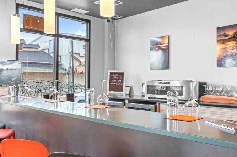 Empty tasting bar with wine glasses, water glasses, and a chalkboard menu, window view behind.